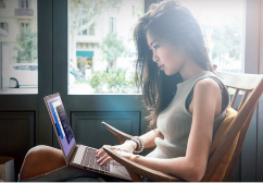 Uma mulher de cabelo preto sentada em uma poltrona mexendo em um notebook Acer