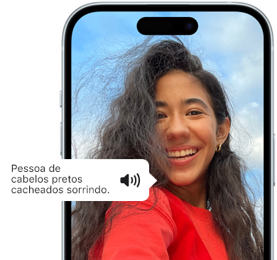 iPhone 15 mostrando um texto anunciado pelo Voiceover que descreve uma foto como: pessoa de cabelos pretos cacheados sorrindo.